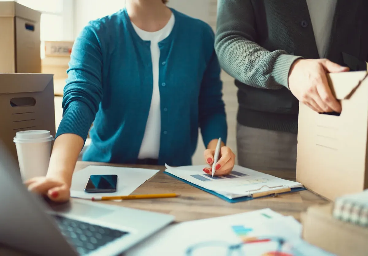 Person creating a moving checklist next to packing boxes